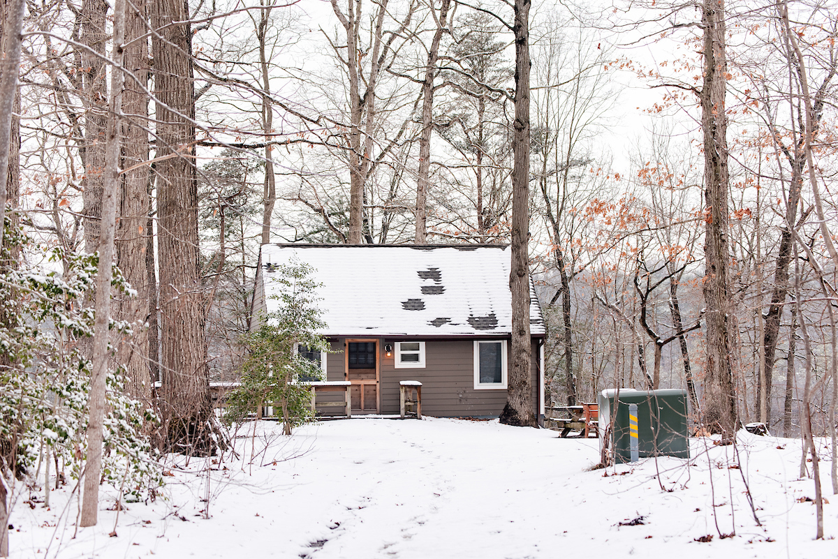 A snow-covered winter cabin in the woods of Killens Pond State Park.